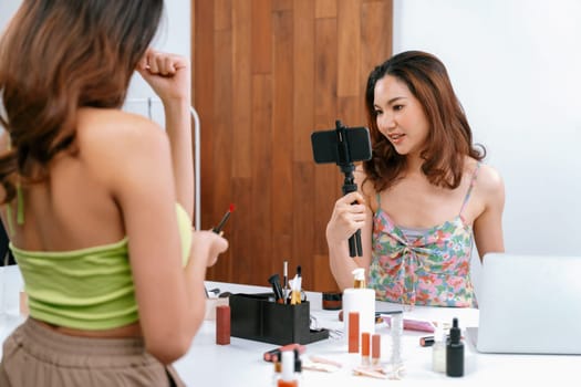 Asian Woman influencer shoot live streaming vlog video review makeup uttermost social media or blog. Happy young girl with cosmetics studio lighting for marketing recording session broadcasting online