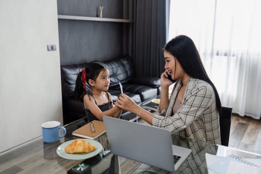 business woman work from home and take care of her child while working, doing activities with her child while talking on mobile.