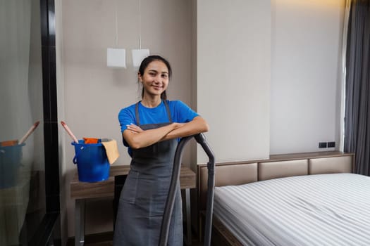 Online cleaning service. Cleaning woman looking at camera and holding a vacuum cleaner.