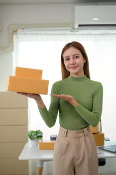 Young business woman asian working online ecommerce shopping at her shop. Young woman sell prepare parcel box of product for deliver to customer. Online selling.