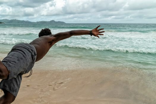 Black man jumping in water in seychelles
