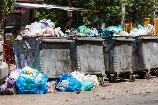 overfilled public trash bins at summer day in Bishkek, Kyrgyzstan - May 26, 2023