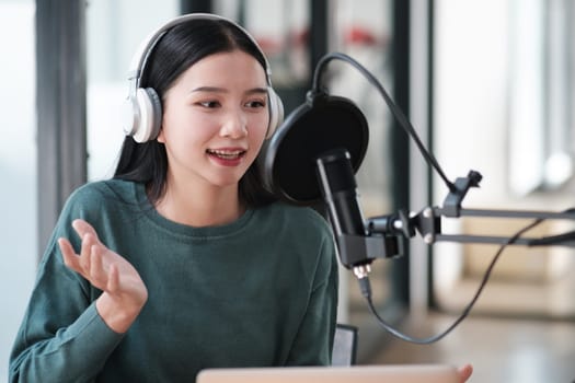 A woman wearing headphones and a microphone is recording a voice. She is smiling and she is happy
