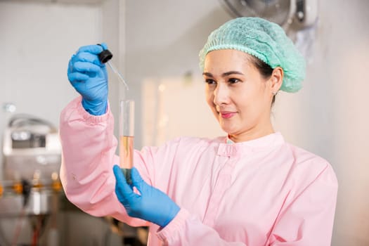 A woman food engineer demonstrates food and beverage quality and safety testing in juice beverage factory employing test tubes to sample basil or chia seeds in bottled products highlighting expertise