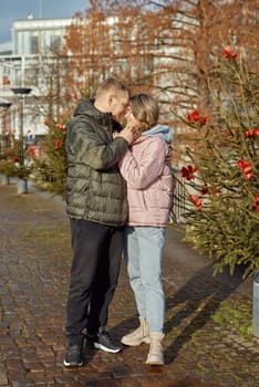 Portrait of young attractive people, lovely couple enjoying cozy atmosphere on fair in Christmas Eve. Spending time together. Concept of national traditions, winter holidays, fashion, festivities