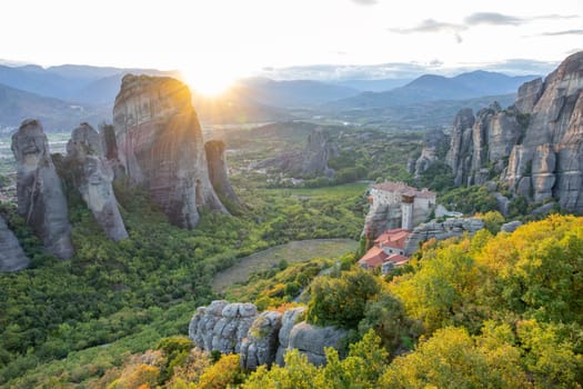 Greece. Sunset rays over the green valley in Meteora. Monastery on the rock