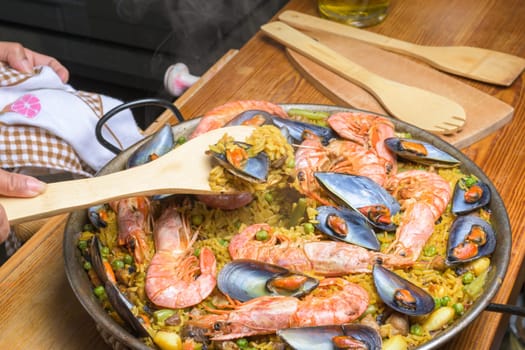 Seafood paella with prawns in a pan beside wooden utensils, typical Spanish cuisine, Majorca, Balearic Islands, Spain,