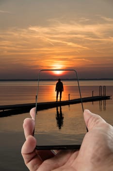 an adult woman stands on a wooden yeti in the lake during sunset in the evening