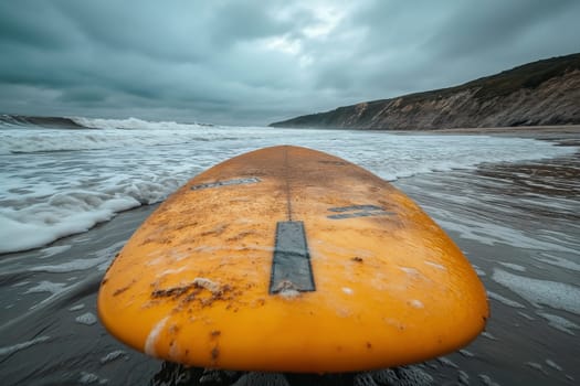 In the foreground is a yellow surfboard on a sandy beach. Beach without people.