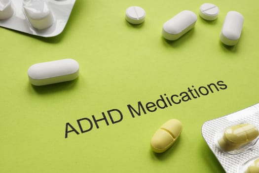 Green sheet of paper with inscription ADHD medications and pills.