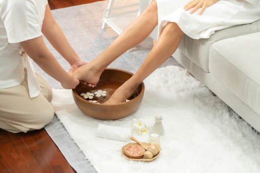 Woman indulges in blissful foot massage at luxurious spa salon while masseur give reflexology therapy in gentle day light ambiance resort or hotel foot spa. Quiescent