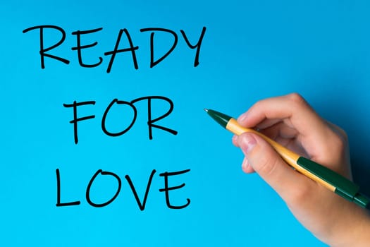 Children hand with pen write on a blue white background. Writing hand. Words Ready for love