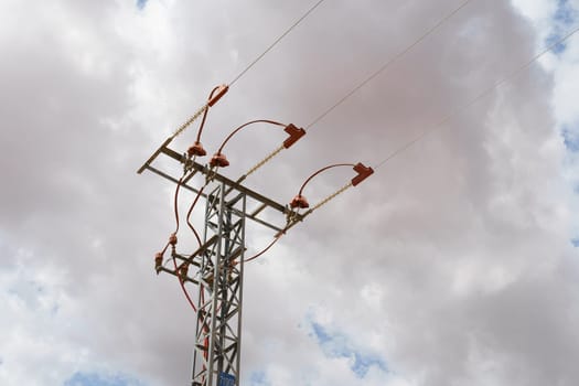 A high voltage power line towers against a clear blue sky, carrying electricity across the landscape.