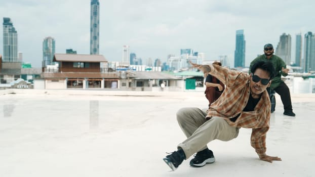 Professional hispanic break dancer practice B boy dance while multicultural friends at roof top. Young modern dancing group doing hip hop movement. Style,fashion,action. Outdoor sport 2024. Endeavor.