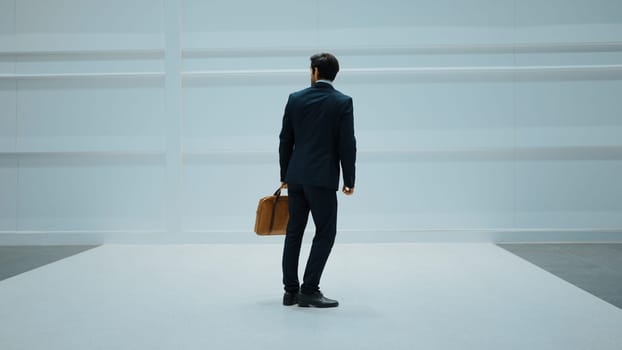 Professional business man standing with cool pose at white background. Manager holding bag while finding partner or looking around. Caucasian working man prepare himself for presentation. Exultant.