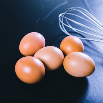 eggs and whisk on a black background