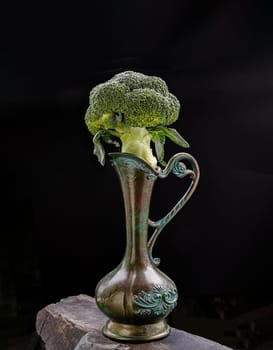 Fresh Green Color Broccoli on Antigue carved iron jug with dark background. Healthy eating concept, Space for text, Selective focus.