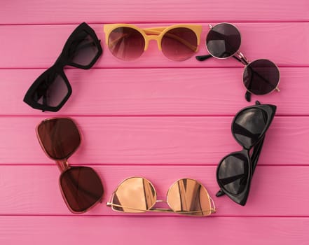 Summer abstract background mockup template free copy space for text pattern sample top view above on pink wooden board. blank empty area for inscription. sunglasses fashionable folded in circle