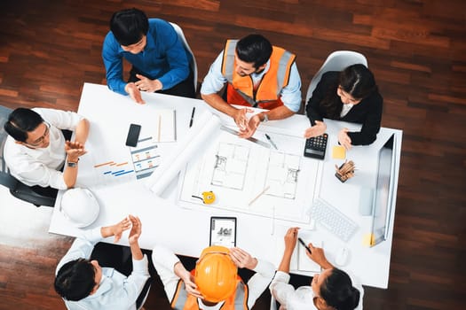 Top view banner of diverse group of civil engineer and client working together on architectural project, reviewing construction plan and building blueprint at meeting table. Prudent