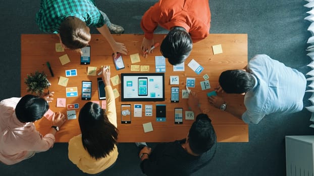 Top view of developer team working together to write idea about Ux Ui design on whiteboard. Smart programmer looking at wireframe prototype at tablet and designing software. Top view. Convocation.