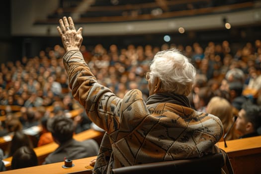 At an art competition event, a man in a wheelchair is raising his hand in front of a crowd. The audience watches his gesture of determination and inclusion