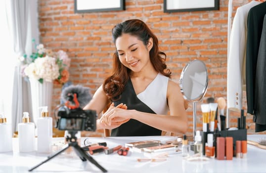 Asian Woman influencer shoot live streaming vlog video review makeup uttermost social media or blog. Happy young girl with cosmetics studio lighting for marketing recording session broadcasting online