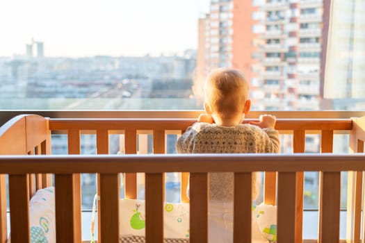 A child stands in front of the window and looks at the city from above.