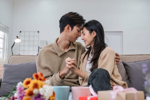 Young couple hugging and showing their love to each other. And give bouquets of flowers to each other on special days or Valentine's Day. On the sofa in the living room.