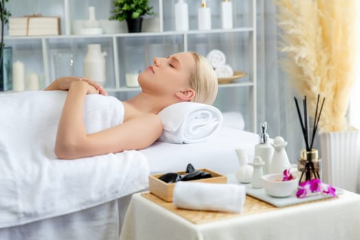 Caucasian woman customer enjoying relaxing anti-stress spa massage and pampering with beauty skin recreation leisure in day light ambient salon spa at luxury resort or hotel. Quiescent