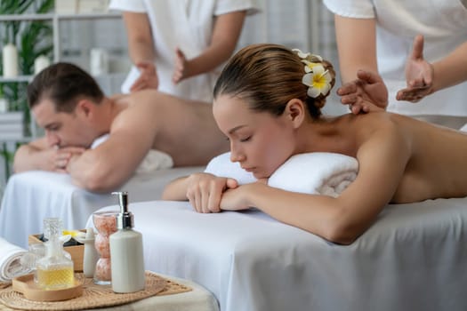 Caucasian couple customer enjoying relaxing anti-stress spa massage and pampering with beauty skin recreation leisure in day light ambient salon spa at luxury resort or hotel. Quiescent