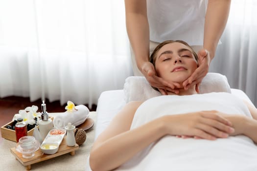 Caucasian woman enjoying relaxing anti-stress head massage and pampering facial beauty skin recreation leisure in dayspa modern light ambient at luxury resort or hotel spa salon. Quiescent