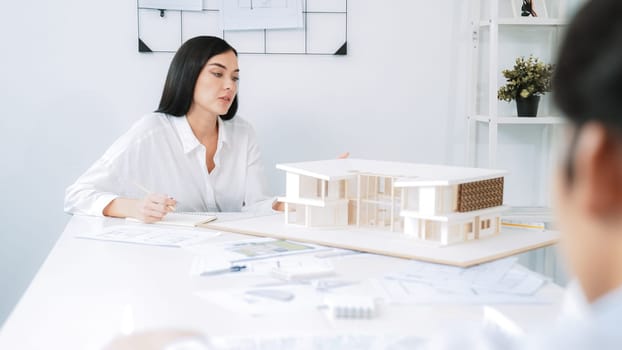 Professional asian male project manager hand puts the map on meeting table while discuss and brainstorm with coworker about building project at meeting room with blueprint hand behind. Immaculate.