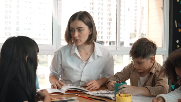 Happy diverse student and smart teacher drawing and coloring by using marker at drawing book. Multicultural smart learner using drawing book while talking to skilled caucasian instructor. Erudition.