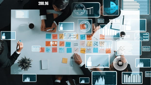 Top down aerial view of smart business people sharing marketing idea by writing sticky notes and placed on meeting table with data analyst holographic or hologram of financial statistic. Directorate.