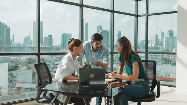 Group of skilled businesspeople sharing idea about marketing plan. Professional business team working together, discussing, talking at meeting table with laptop, document with cityscape. Tracery