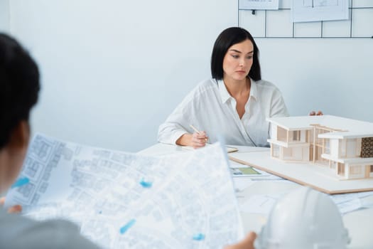 Closeup image of professional cooperative engineer team discuss about building location at modern office. Male engineer put the map on table while beautiful architect taking a note. Immaculate.