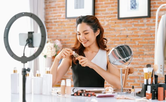 Asian Woman influencer shoot live streaming vlog video review makeup uttermost social media or blog. Happy young girl with cosmetics studio lighting for marketing recording session broadcasting online