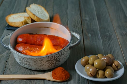 typical spanish tapa ,chorizo to hell in ceramic casserole accompanied by bread and olives