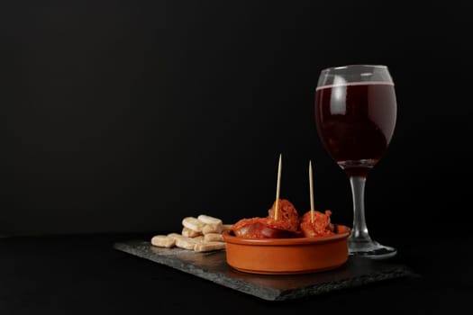 chorizo frito ,typical spanish tapa in a clay pot accompanied by bread and a glass of red wine.