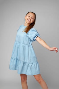 Young happy smiling woman in a light blue dress on a gray background close up