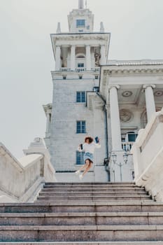 Woman staircase city. A business woman in a white shirt and denim skirt walks down the steps of an ancient building in the city.