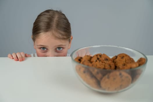 A little girl tries to steal cookies from the table