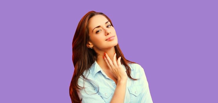 Portrait of beautiful young brunette woman model posing on purple studio background