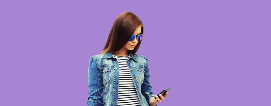Modern stylish young woman with mobile phone on purple studio background