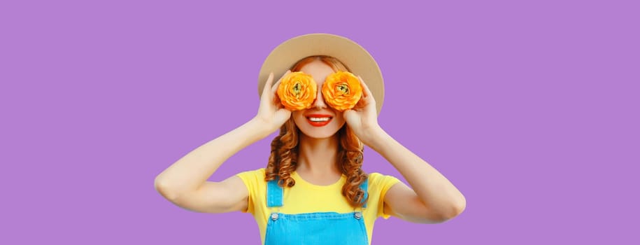 Summer portrait of happy smiling woman covering her eyes with flower buds as binoculars looking for something in straw hat on purple studio background