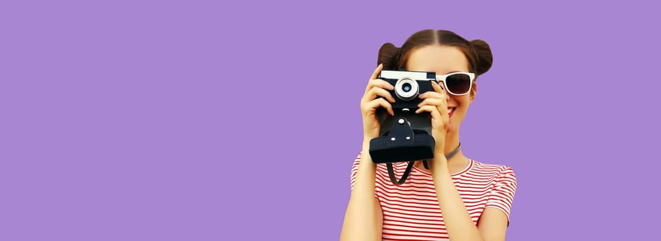 Portrait of happy young woman photographer with film camera, female on violet studio background, copy space for advertising text