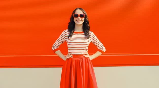 Beautiful happy smiling young brunette woman model posing in red heart shaped sunglasses, skirt on city street