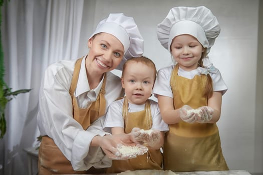 Cute oriental family with mother, daughter, son cooking in kitchen on Ramadan, Kurban-Bairam, Eid al-Adha. Funny family at a cook photo shoot. Pancakes, Maslenitsa, Easter
