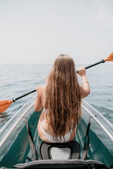 Woman in kayak back view. Happy young woman with long hair floating in transparent kayak on the crystal clear sea. Summer holiday vacation and cheerful female people having fun on the boat.