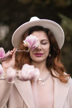 Woman holds magnolia flowers, surrounded by blossoming trees. Captured during spring, showcasing natural beauty and seasonal change